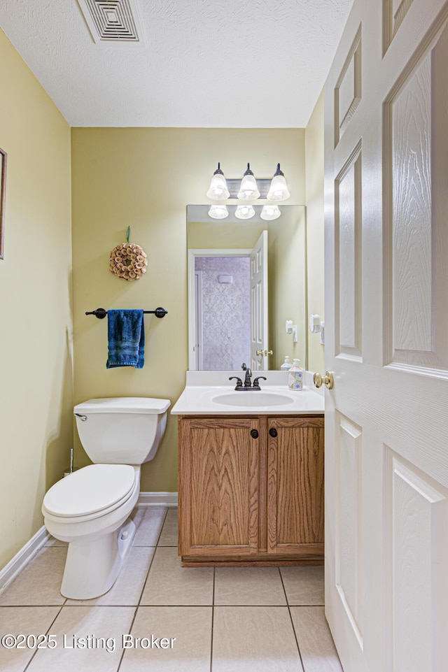 bathroom featuring vanity, toilet, tile patterned flooring, and a textured ceiling