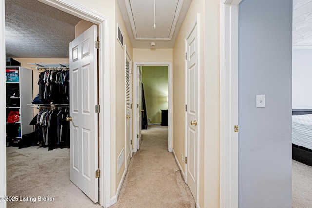 hallway with light carpet and a textured ceiling