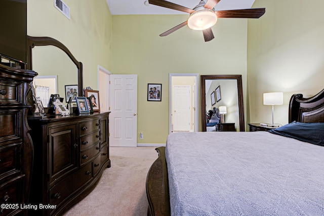 bedroom featuring light carpet, ceiling fan, and a high ceiling