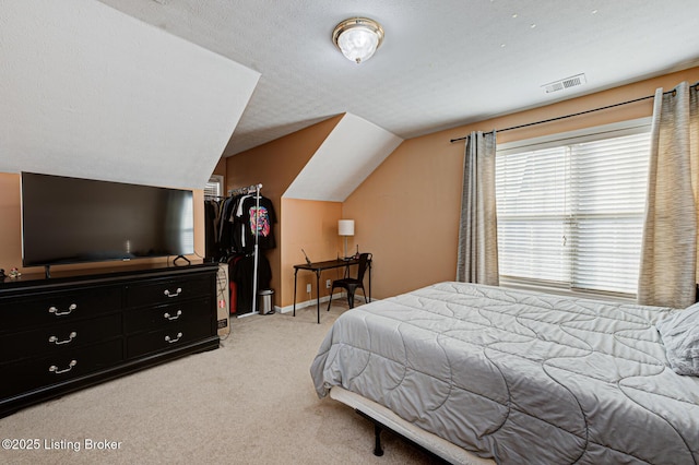 bedroom with vaulted ceiling, light colored carpet, and a textured ceiling