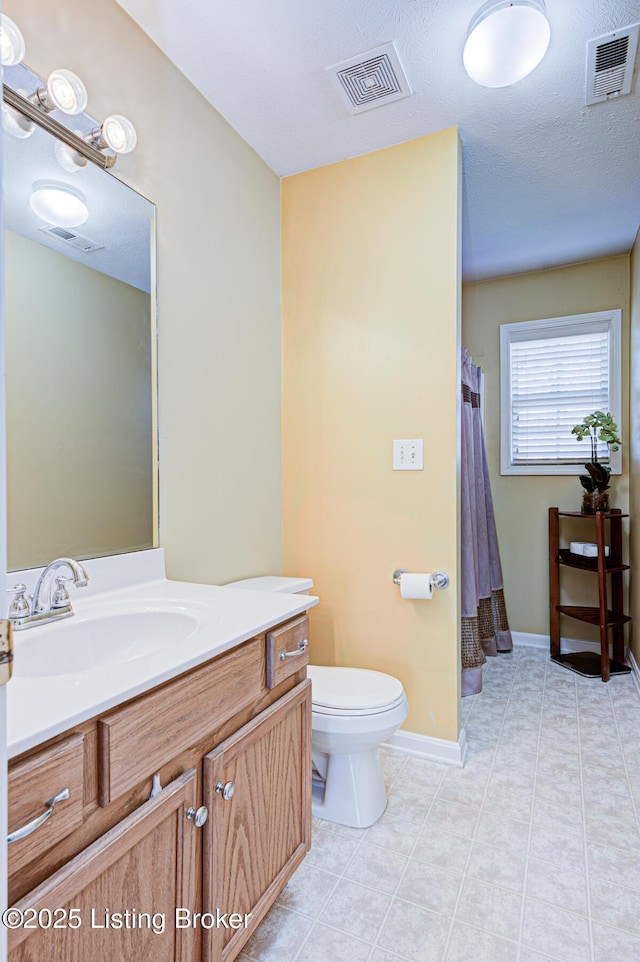 bathroom with tile patterned flooring, vanity, a textured ceiling, and toilet