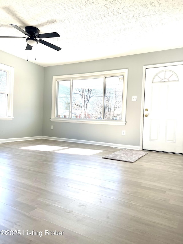 foyer entrance with ceiling fan, a textured ceiling, and light hardwood / wood-style floors