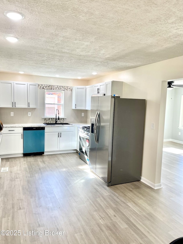 kitchen with sink, appliances with stainless steel finishes, tasteful backsplash, light hardwood / wood-style floors, and white cabinets