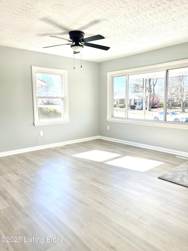 spare room with ceiling fan, a textured ceiling, and light hardwood / wood-style flooring