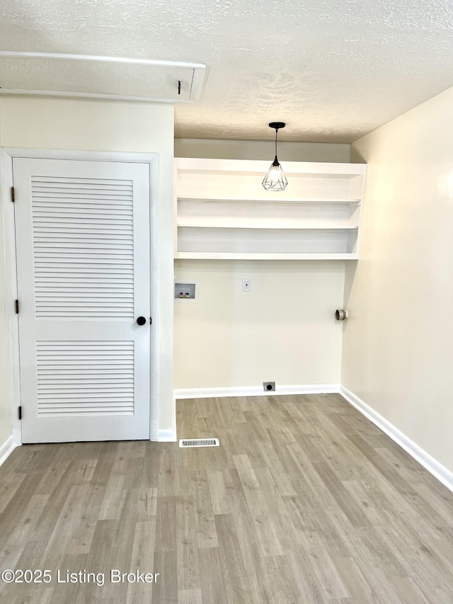 washroom featuring hookup for a washing machine, electric dryer hookup, a textured ceiling, and light hardwood / wood-style flooring