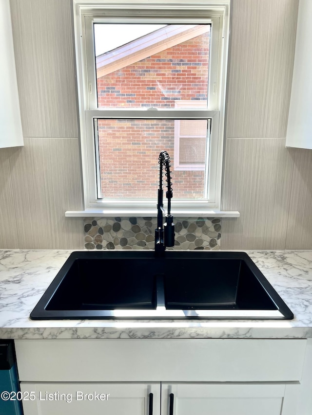 room details featuring tasteful backsplash, sink, and light stone counters