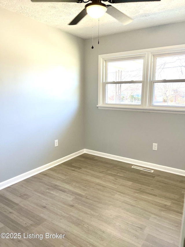 spare room with ceiling fan, hardwood / wood-style flooring, and a textured ceiling