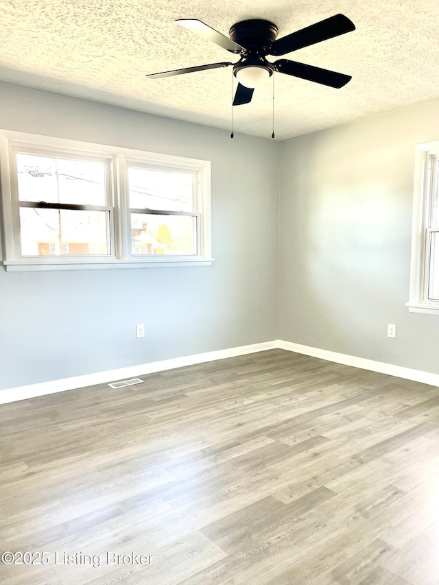 spare room with a textured ceiling, light hardwood / wood-style flooring, and a wealth of natural light