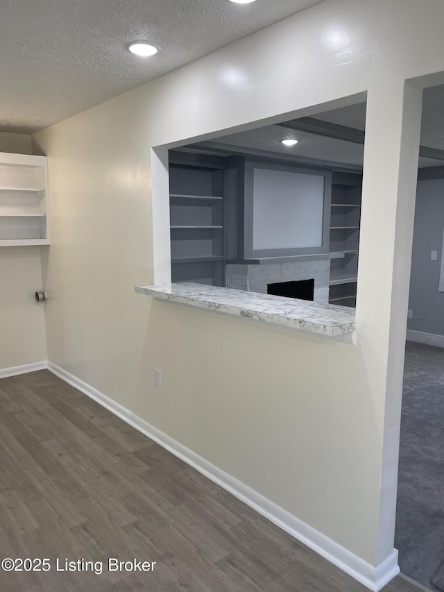 interior space featuring built in features, dark hardwood / wood-style floors, and a textured ceiling