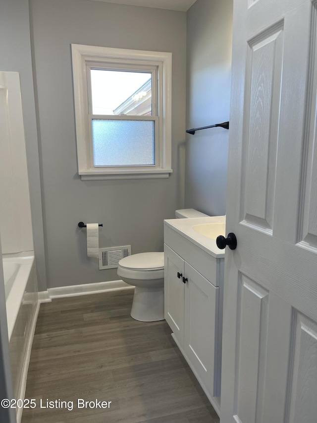 bathroom with vanity, a bathtub, hardwood / wood-style flooring, and toilet