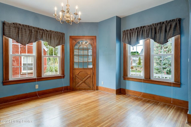 unfurnished room featuring a notable chandelier, hardwood / wood-style flooring, and a wealth of natural light