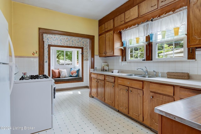 kitchen with sink, white appliances, and a healthy amount of sunlight