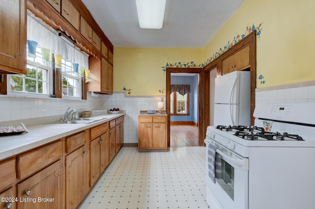 kitchen featuring tile walls, sink, white appliances, and a wealth of natural light