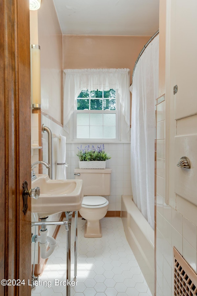 full bathroom with tile patterned floors, toilet, and tile walls