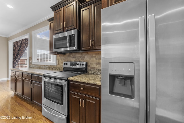 kitchen with tasteful backsplash, ornamental molding, appliances with stainless steel finishes, and dark brown cabinets