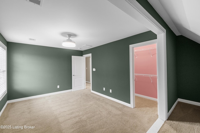 unfurnished bedroom with a walk in closet, a closet, and carpet