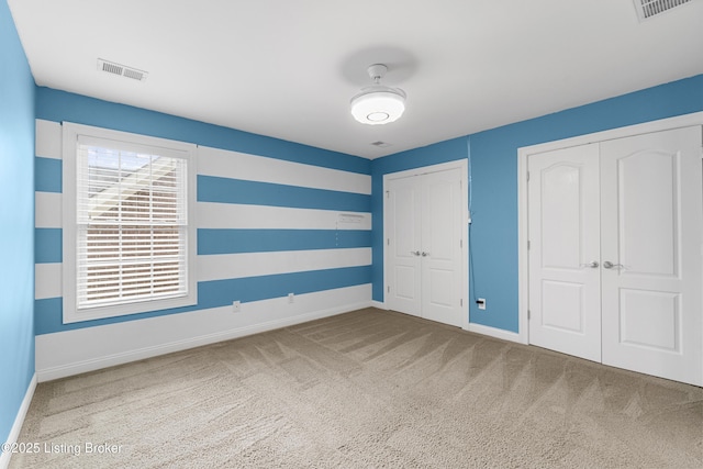 unfurnished bedroom with multiple closets and carpet