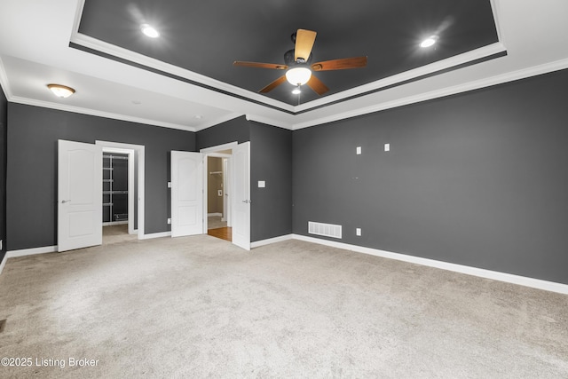 unfurnished bedroom with crown molding, a tray ceiling, and light carpet