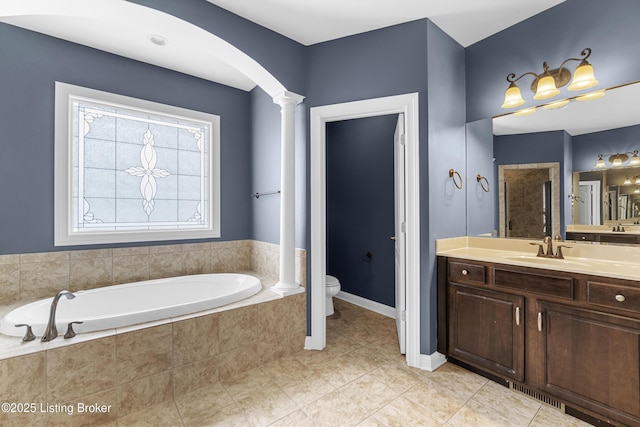 bathroom featuring tile patterned floors, toilet, vanity, tiled bath, and decorative columns