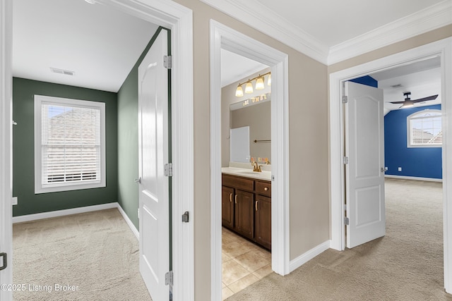 hallway with light carpet, sink, and crown molding