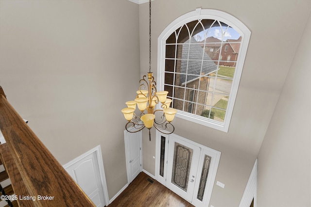 entrance foyer with dark wood-type flooring, an inviting chandelier, and a towering ceiling