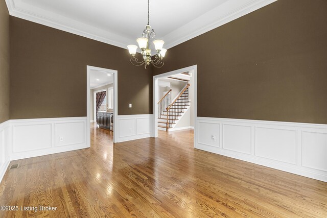 empty room featuring crown molding, a chandelier, and light wood-type flooring