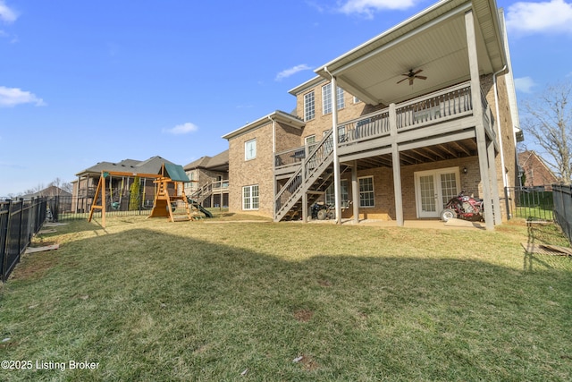 back of house featuring ceiling fan, a lawn, a playground, and a deck