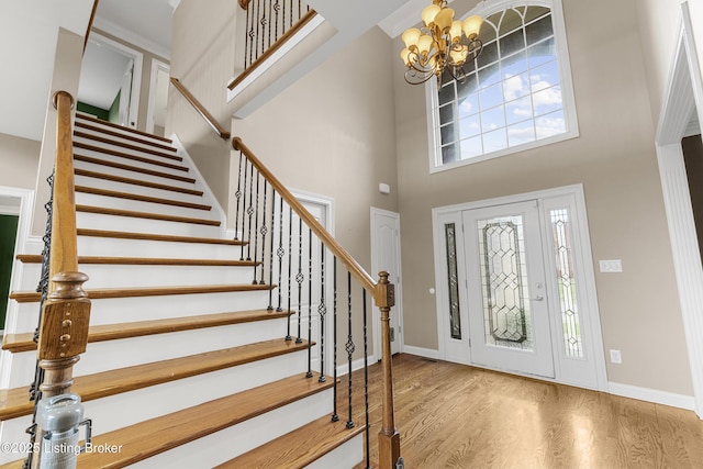 foyer entrance with an inviting chandelier, a towering ceiling, and wood-type flooring