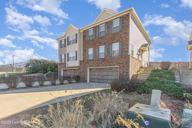 view of front of house with concrete driveway, brick siding, stairway, and an attached garage