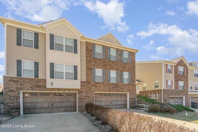 townhome / multi-family property featuring a garage, concrete driveway, and brick siding