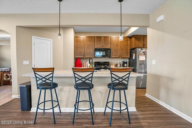 kitchen with pendant lighting, dark hardwood / wood-style flooring, a breakfast bar, and black appliances