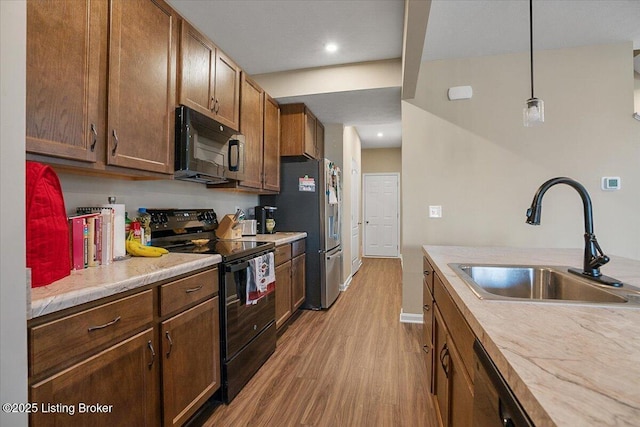 kitchen with sink, decorative light fixtures, light hardwood / wood-style flooring, and black appliances