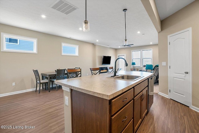 kitchen with pendant lighting, sink, dark hardwood / wood-style flooring, and a center island with sink