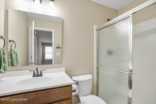 bathroom with walk in shower, vanity, and toilet