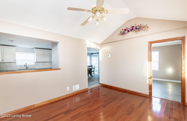 spare room with vaulted ceiling, ceiling fan, sink, and hardwood / wood-style floors