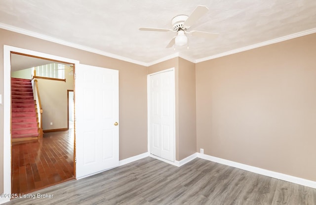 unfurnished bedroom featuring crown molding, hardwood / wood-style floors, ceiling fan, and a closet