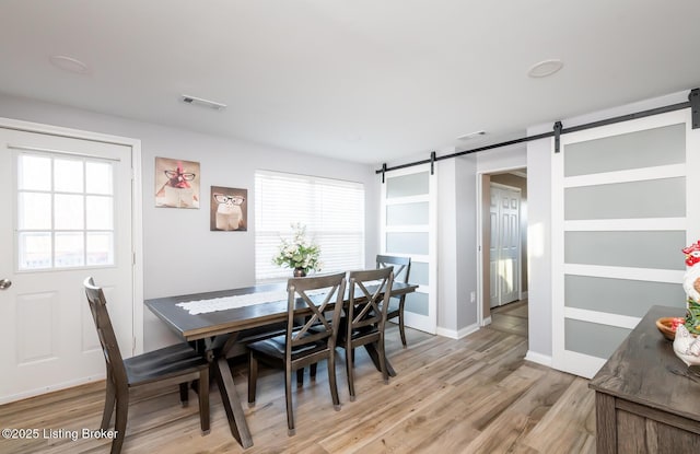 dining room with a barn door and light wood-type flooring