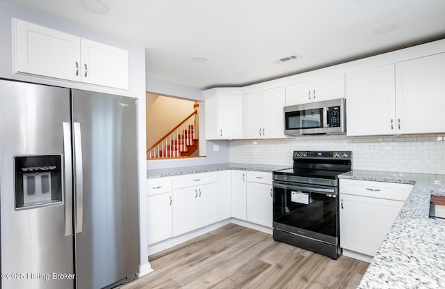 kitchen with white cabinetry, backsplash, and appliances with stainless steel finishes