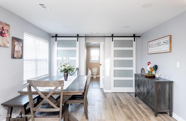 dining area featuring a barn door and light wood-type flooring