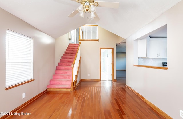 stairs with lofted ceiling, hardwood / wood-style flooring, and ceiling fan