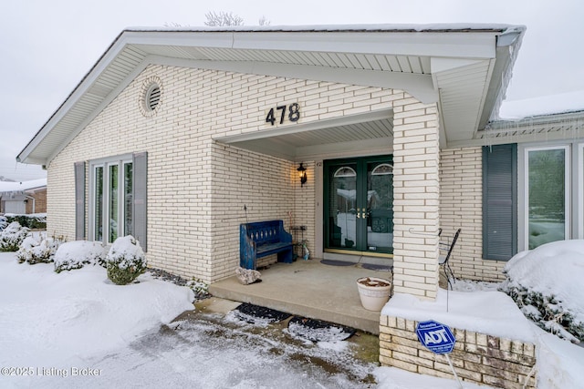 snow covered property entrance with a porch