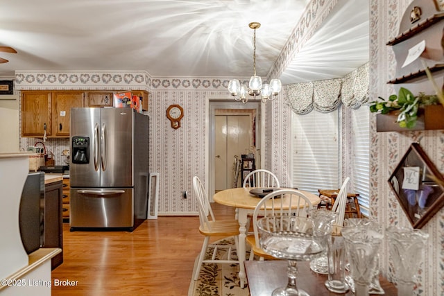 dining space with ceiling fan with notable chandelier and light wood-type flooring