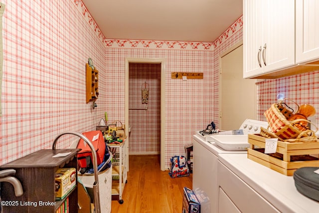 clothes washing area featuring cabinets, washer and clothes dryer, and light hardwood / wood-style floors