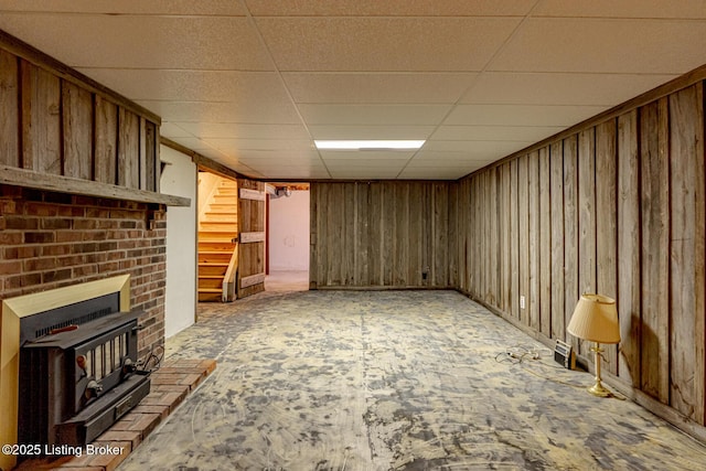 unfurnished living room with a paneled ceiling and a wood stove