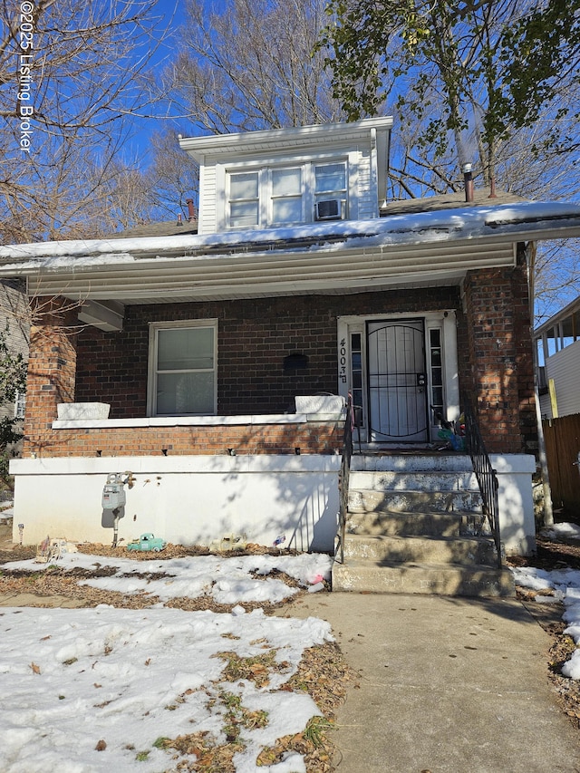 snow covered property entrance featuring covered porch