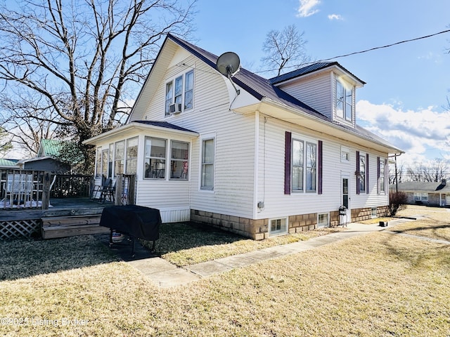 view of home's exterior with a sunroom, a deck, and a lawn