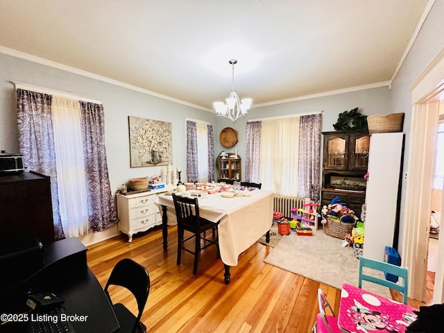 dining room with ornamental molding, a chandelier, radiator heating unit, and light wood-type flooring