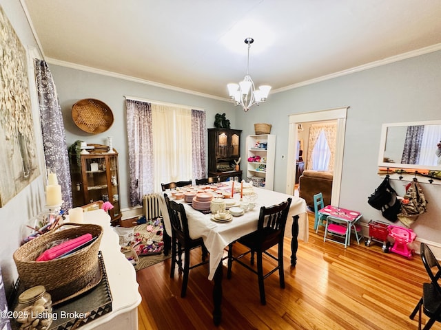 dining area with ornamental molding, hardwood / wood-style floors, and a chandelier