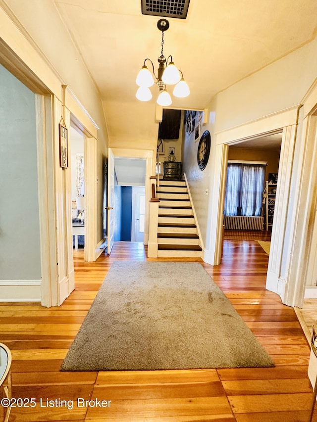 corridor featuring an inviting chandelier and hardwood / wood-style floors