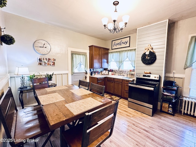 dining room featuring radiator, a chandelier, and light wood-type flooring